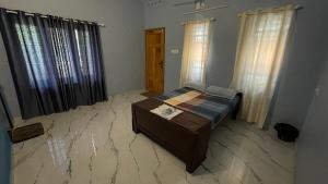 a bedroom with a bed and a table and windows at Olive Homestays in Varkala