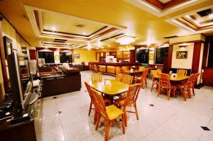 a dining room with tables and chairs and a kitchen at Abbo Hotel in Tainan