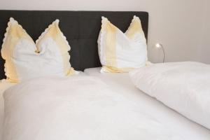 two beds with white sheets and yellow and white pillows at Landhaus Kauderer - Wohnung 1 in Waging am See +2 photos