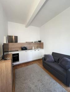 Una sala de estar con un sofá y una cocina. en Studio design aux portes de Paris, en Gennevilliers