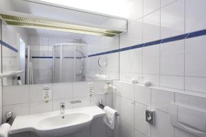 a white bathroom with a sink and a mirror at Romantik Hotel Störmann in Schmallenberg +25 photos