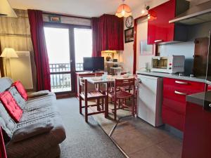 una cucina con armadi rossi, tavolo e divano di Studio 4 pers avec balcon et parking couvert - FR-1-340-50 a Chamrousse