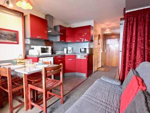 una cucina con armadi rossi, tavolo e divano di Studio 4 pers avec balcon et parking couvert - FR-1-340-50 a Chamrousse Altre 12 foto
