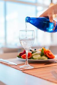 a person pouring water from a blue bottle into a wine glass at Port Europa in Calpe