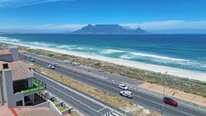 a road with cars on it next to the ocean at Beach Daze in Bloubergstrand