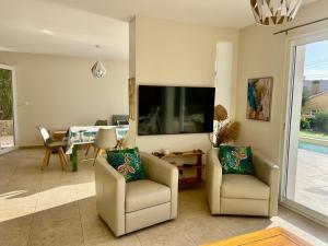a living room with two chairs and a flat screen tv at Villa Ischia Vue Mer in Bandol