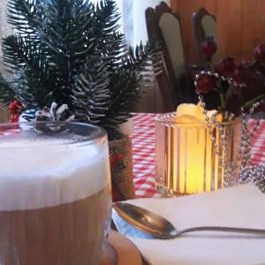 a table with a glass of drink and a christmas tree at Dlya Vseh Motel in Kamianets-Podilskyi