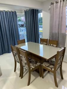 a dining room table and chairs with blue curtains at Ap novo e climatizado no centro com ótima localização na avenida principal in Piratuba