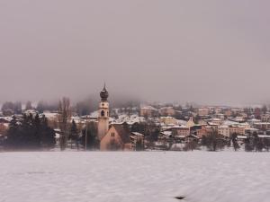 a snow covered town with a clock tower in the distance at Casa della Lavanda in Sarnonico