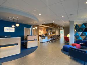 un vestíbulo con paredes azules, mesas y sillas en Holiday Inn Express Caen Epron by IHG, en Caen