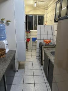 a small kitchen with white tile floors and counters at Apartamento na praia de Bombas Edifício Umuarama nº 63, bloco B in Bombinhas +1 photo