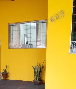 a yellow wall with a window and a plant at Família Durães Kitnets01 in Londrina