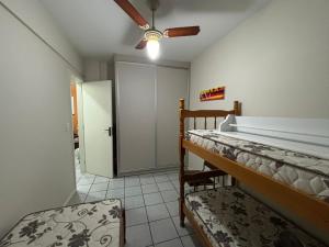 a bedroom with two bunk beds and a ceiling fan at Apartamento na praia de Bombas Edifício Umuarama nº 63, bloco B in Bombinhas