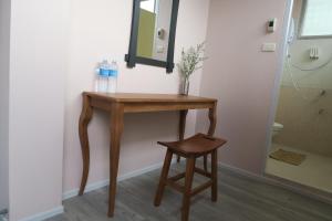 a wooden table and stool in a bathroom with a mirror at The Grand Palace Hotel in Bangkok