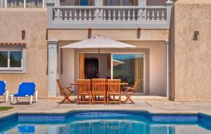 een tafel met stoelen en een parasol naast een zwembad bij Villa The Pond in Sant Josep