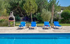 een groep blauwe stoelen en een tafel naast een zwembad bij Villa The Pond in Sant Josep