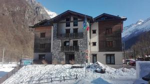 a building in the snow in front of a mountain at Casa Corti Ostello Ristorante in Valbondione