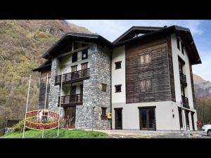 a large wooden building with a playground in front of it at Casa Corti Ostello Ristorante in Valbondione