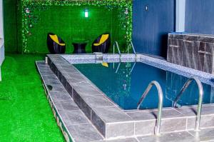 una piscina con césped verde y sillas en una habitación en 2 Bedroom Luxury Apartment with Pool -24Hrs Power -PS4, en Lagos