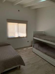 Un dormitorio con dos literas y una ventana. en Casa en Sauce Grande - Calvario, en Balneario Sauce Grande