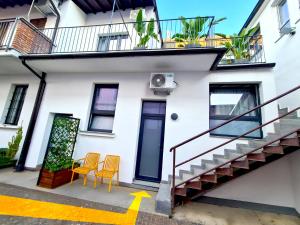 a white house with two chairs and a staircase at Be Magenta, Art Home - Yellow style - Near Milano, Rho Fiera, Malpensa in Magenta