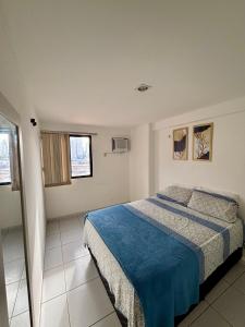 a bedroom with a bed with a blue blanket at Apartamento Amplo - Ideal para famílias in João Pessoa