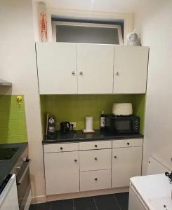 ヌイイ・シュル・セーヌにあるParis Neuilly Défenseの白いキャビネットと電子レンジを備えたキッチン +6枚の写真