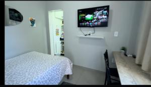 a bedroom with a bed and a tv on the wall at Nº11- Mini Apto 5 min do Centro ar cond, cozinha e garagem in Divinópolis