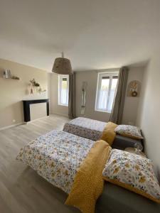 ein Schlafzimmer mit zwei Betten und zwei Fenstern in der Unterkunft Maison IDEM in Vouziers