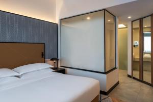 a bedroom with a white bed and a glass wall at Sheraton Mall of the Emirates Hotel, Dubai in Dubai