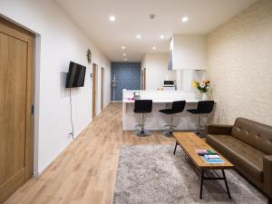 een woonkamer met een bank en een keuken bij OASIS NANIWA in Osaka