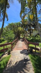 un pont en bois sur un chemin planté de palmiers dans l'établissement Casa Lírio - Beira da praia, à Porto Seguro