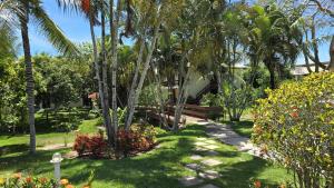 un jardin avec un banc, des palmiers et des fleurs dans l'établissement Casa Lírio - Beira da praia, à Porto Seguro 20 autres photos