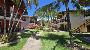 un chemin à travers la cour d'un complexe hôtelier avec des palmiers dans l'établissement Casa Lírio - Beira da praia, à Porto Seguro