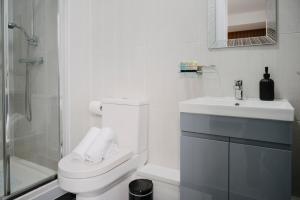 a white bathroom with a toilet and a sink at WNS Skylines Village in London +23 photos