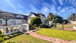 a house with a white fence and a yard at Lagoon Lodge in Cape Town
