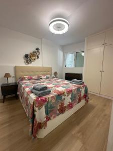 Un dormitorio con una cama con una colcha floral. en The pool balcony Playa las Americas, en Csta Adje
