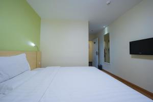 a bedroom with a large white bed and a flat screen tv at 7Days Premium Guangzhou Tianhe Shipaiqiao in Guangzhou