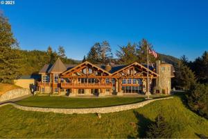 an image of a large log home with a flag at LX28: Gold Beach Oceanfront Estate in Ophir