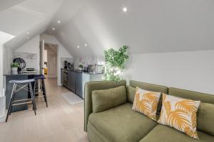 a living room with a green couch and a kitchen at 1 Bedroom Penthouse Apartment - Shoreditch, London by The Perfect Stay in London +9 photos