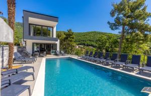 a swimming pool with chairs and a house at Beautiful Villa Magica in Opatija in Mošćenička Draga