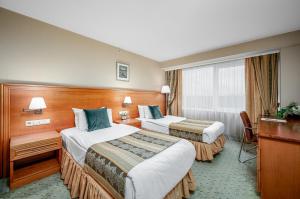 a hotel room with two beds and a desk at VILNIUS PARK PLAZA HOTEL & SPA, Restaurant, Conference & Banquet Center in Vilnius