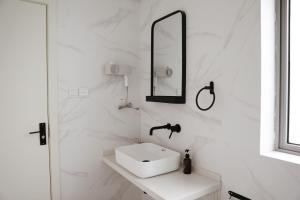 un bagno bianco con lavandino e specchio di Bujuexiao Inn Yuki House Luda Rd a Shanghai