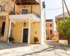 a yellow house with a balcony on a street at Nina's Traditional House By Estia in Valaneíon