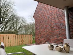a table with vases on it next to a brick wall at Landblick 1 - Luxusferienwohnung für 4 Personen in Norddeich