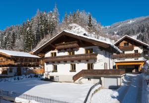 budynek pokryty śniegiem z płotem z przodu w obiekcie Haus Schneeberg mit Hochkönig Card w mieście Mühlbach am Hochkönig