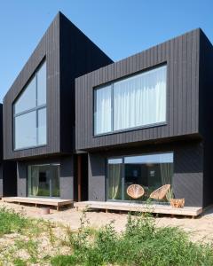 una casa negra con dos sillas delante en Svencelės burė 10, en Svencelė