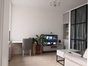 a white living room with a couch and a tv at Mario Studio in Vilnius