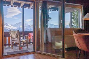 a room with glass doors and a chair on a balcony at Chalet Rübezahl 1 OG in Riederalp