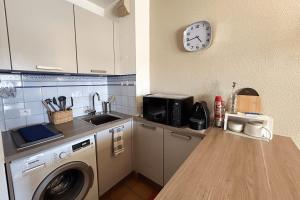 a kitchen with a washing machine and a clock on the wall at This comfortable and bright apartment WIFI in Grimaud